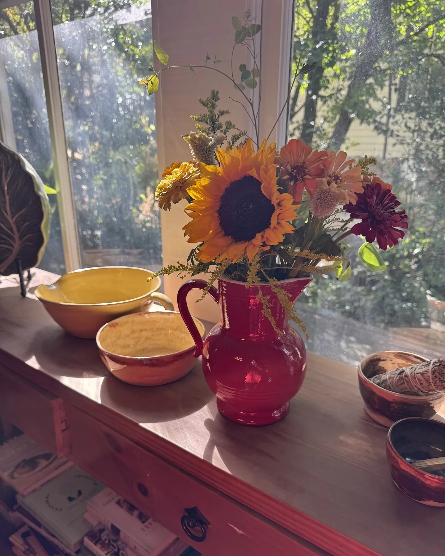 Sunflowers and colorful flowers arranged in a red pitcher